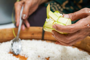 Ketupat yapma süreci bayramda geleneksel bir yemektir. Pirinci ketupat kutusuna koy..