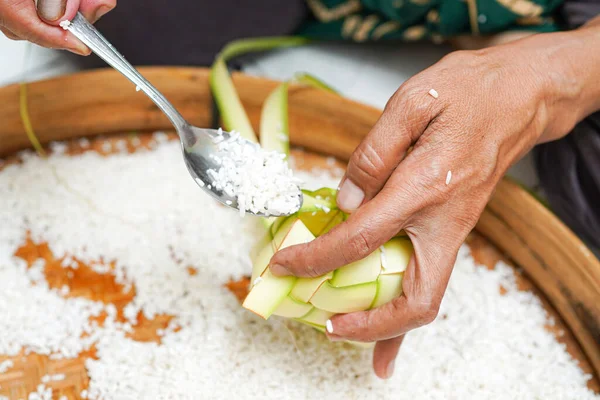 Ketupat yapma süreci bayramda geleneksel bir yemektir. Pirinci ketupat kutusuna koy..