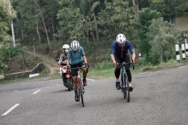 Yokuş yukarı giden yolda bisiklet sürücülerinin ifadesi ve stili, Ambarrukmo 2022 Tur için test rotasına hazırlanıyor.: Sleman, Endonezya - 21 Mayıs 2022