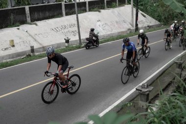 Yokuş yukarı giden yolda bisiklet sürücülerinin ifadesi ve stili, Ambarrukmo 2022 Tur için test rotasına hazırlanıyor.: Sleman, Endonezya - 21 Mayıs 2022