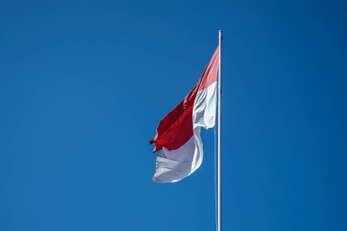 Mavi gökyüzü arkaplanlı Endonezya bayrağı.