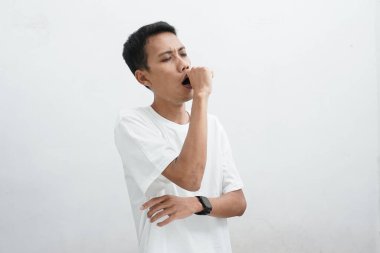 Asyalı adam uykulu esneme, ayakta uyuma, beyaz arka planda yarım vücut portresi.