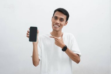 Akıllı telefon kullanan Asyalı bir adam. Telefona bakıyor ve çok şaşırmış görünüyor. Beyaz arka planda beyaz bir tişört giyiyor..