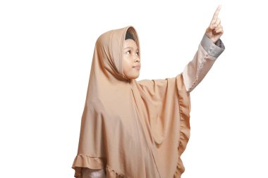 girl wearing a hijab, wearing a brown Muslim dress who is pointing to an empty space on a white background