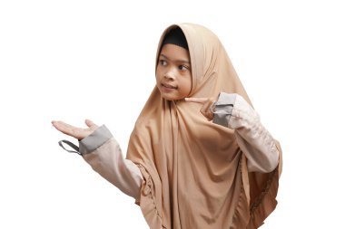 girl wearing a hijab, wearing a brown Muslim dress who is pointing to an empty space on a white background