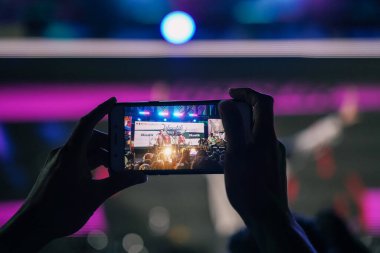 Point of view, the audience is taking photos or recording using a smartphone the appearance of the preferred musician. On the stage was Jikustik band. : Yogyakarta, Indonesia - 07 September 2022