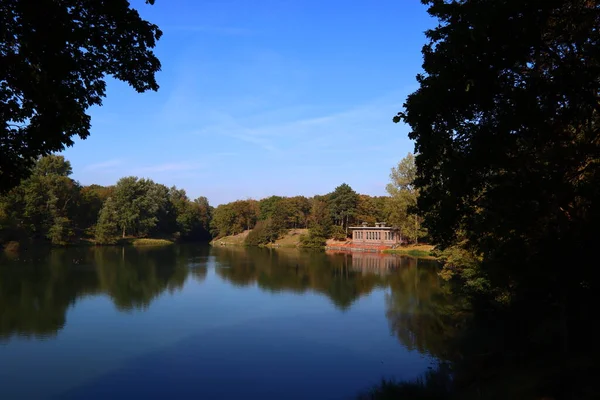 Piękne Jezioro Parku Spokojna Niebieska Woda Duże Zielone Drzewa Błękitne — Zdjęcie stockowe