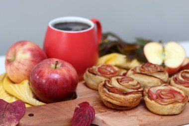 Bir fincan siyah çay, kırmızı elmalar ve masada tatlı bir pasta. Canlı yemek fotoğrafı. Elmalı pastalar kapanıyor..