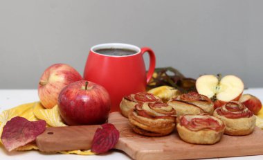 Bir fincan siyah çay, kırmızı elmalar ve masada tatlı bir pasta. Canlı yemek fotoğrafı. Elmalı pastalar kapanıyor..