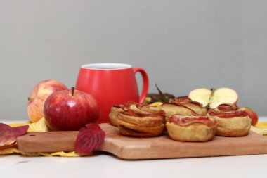 Bir fincan siyah çay, kırmızı elmalar ve masada tatlı bir pasta. Canlı yemek fotoğrafı. Elmalı pastalar kapanıyor..
