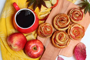 Bir fincan siyah çay, kırmızı elmalar ve masada tatlı bir pasta. Canlı yemek fotoğrafı. Elmalı pastalar kapanıyor..