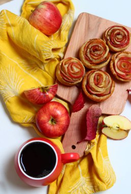 Elmalı turtalar, kırmızı yapraklar ve sarı mutfak havlusuyla dolu bir hayat. Yeni pişmiş elmalı keklerin en iyi görüntüsü. Tatlı sonbahar menüsü. 
