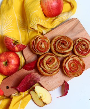Elmalı turtalar, kırmızı yapraklar ve sarı mutfak havlusuyla dolu bir hayat. Yeni pişmiş elmalı keklerin en iyi görüntüsü. Tatlı sonbahar menüsü. 