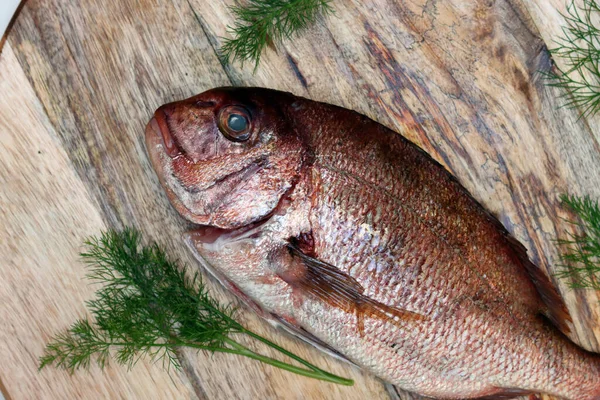 木の板の上で新鮮な魚 テーブルの上で調理されていないドラダ魚 健康的な食事のコンセプト — ストック写真