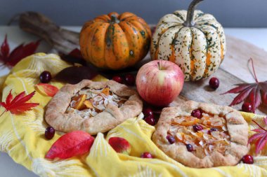 Balkabaklı börekler, kırmızı akçaağaç yaprakları ve masa üzerindeki dekoratif kabak. Sonbahar yemeği. Mevsimlik sebzeler ve balkabağı turtasıyla. 