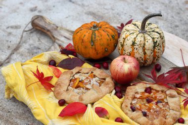 Balkabaklı börekler, kırmızı akçaağaç yaprakları ve masa üzerindeki dekoratif kabak. Sonbahar yemeği. Mevsimlik sebzeler ve balkabağı turtasıyla. 