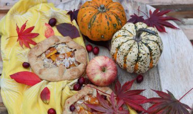 Balkabaklı börekler, kırmızı akçaağaç yaprakları ve masa üzerindeki dekoratif kabak. Sonbahar yemeği. Mevsimlik sebzeler ve balkabağı turtasıyla. 