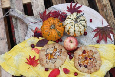 Balkabaklı börekler, kırmızı akçaağaç yaprakları ve masa üzerindeki dekoratif kabak. Sonbahar yemeği. Mevsimlik sebzeler ve balkabağı turtasıyla. 