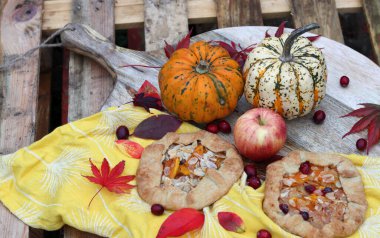Balkabaklı börekler, kırmızı akçaağaç yaprakları ve masa üzerindeki dekoratif kabak. Sonbahar yemeği. Mevsimlik sebzeler ve balkabağı turtasıyla. 