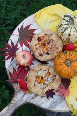 Balkabaklı börekler, kırmızı akçaağaç yaprakları ve masa üzerindeki dekoratif kabak. Sonbahar yemeği. Mevsimlik sebzeler ve balkabağı turtasıyla. 