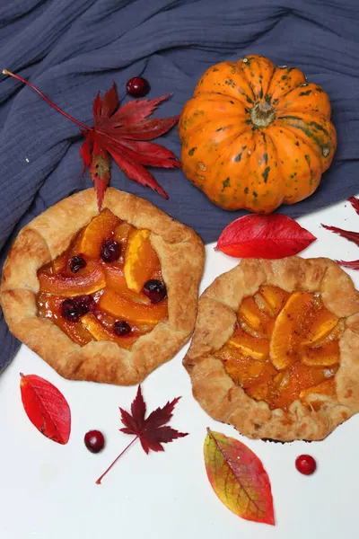 Balkabaklı börekler, kırmızı akçaağaç yaprakları ve masa üzerindeki dekoratif kabak. Sonbahar yemeği. Mevsimlik sebzeler ve balkabağı turtasıyla. 