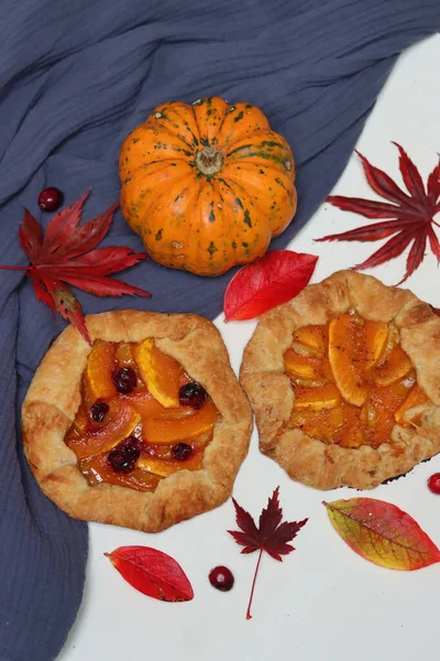 Balkabaklı börekler, kırmızı akçaağaç yaprakları ve masa üzerindeki dekoratif kabak. Sonbahar yemeği. Mevsimlik sebzeler ve balkabağı turtasıyla. 