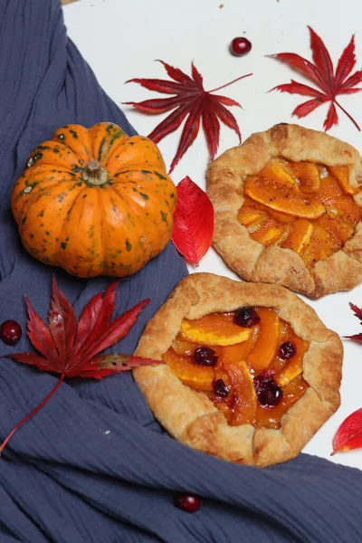 Balkabaklı börekler, kırmızı akçaağaç yaprakları ve masa üzerindeki dekoratif kabak. Sonbahar yemeği. Mevsimlik sebzeler ve balkabağı turtasıyla. 