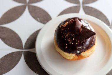 Traditional Israeli doughnut on a white plate. Chocolate doughnut close up photo. Authentic sweets of Middle East. 