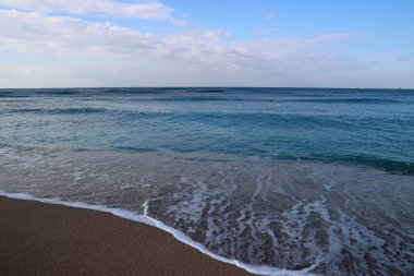 Boş plaj fotoğrafı. Sakin deniz suyu, kum ve insan olmayan güzel sahil şeridi.. 