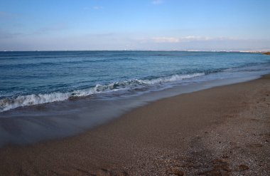 Boş plaj fotoğrafı. Sakin deniz suyu, kum ve insan olmayan güzel sahil şeridi.. 
