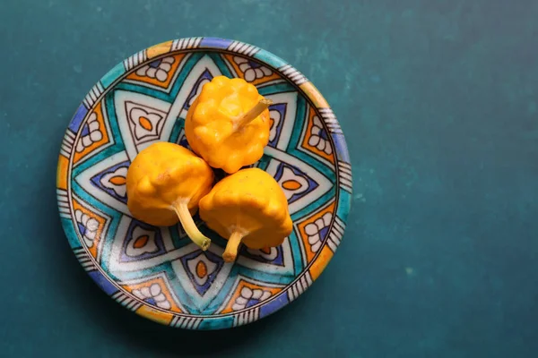 Patty pan squash on decorative ceramic plate. Sill life with vegetables. Beautiful yellow patty pan squashes close up photo.  Textured background with copy space.