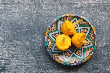 Patty tavayı dekoratif seramik tabakta ezer. Sebzelerle dolu bir hayat. Güzel sarı köfte kabakları yakın plan fotoğraf. Kopyalama alanı olan desenli arkaplan. 