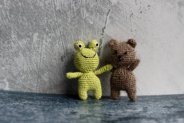Cute crochet toys on grey background. Hand made Tiny bear and frog.