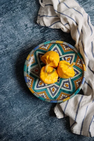 Patty pan squash on decorative ceramic plate. Sill life with vegetables. Beautiful yellow patty pan squashes close up photo.  Textured background with copy space.