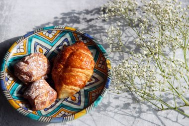 Seramik tabakta kruvasan. Pasta parçalarının fotoğrafını kapat. Tatlı yemek. Hayat fotoğrafı..  
