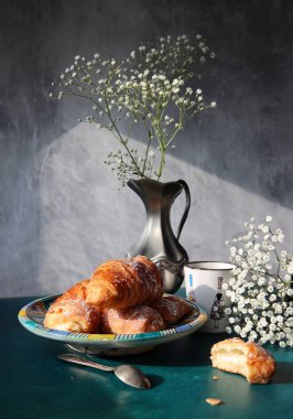 Günaydın! Günaydın! Masada sade kahve ve kruvasan. Hamur işleri ve çiçeklerle dolu güneşli bir resim. Yemek, natürmort. 