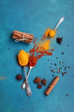 Canlı mavi arka planda aromatik baharatların renkli bir görüntüsü. Zerdeçal, biber, anason, tuz, sarımsak, tarçın yakın plan fotoğraf.. 