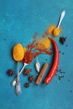Fotokopi alanı olan canlı mavi arka planda farklı baharatlara sahip renkli natürmort yaşam. Paprika, zerdeçal, tarçın, anason, biber ve sarımsak.. 
