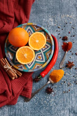 Portakallar, kırmızı biber, kırmızı biber tozu, zerdeçal ve üst görüntü fotoğrafı. Baharatlar masada. Baharatlı yemek hazırlığı yapılıyor. Meyveli renkli natürmort. 