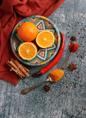 Portakallar, kırmızı biber, kırmızı biber tozu, zerdeçal ve üst görüntü fotoğrafı. Baharatlar masada. Baharatlı yemek hazırlığı yapılıyor. Meyveli renkli natürmort. 