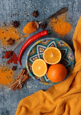 Portakallar, kırmızı biber, kırmızı biber tozu, zerdeçal ve üst görüntü fotoğrafı. Baharatlar masada. Baharatlı yemek hazırlığı yapılıyor. Meyveli renkli natürmort. 