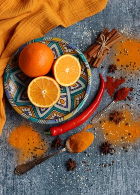 Portakallar, kırmızı biber, kırmızı biber tozu, zerdeçal ve üst görüntü fotoğrafı. Baharatlar masada. Baharatlı yemek hazırlığı yapılıyor. Meyveli renkli natürmort. 
