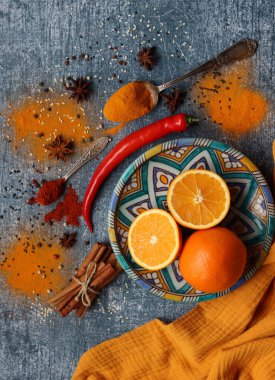 Portakallar, kırmızı biber, kırmızı biber tozu, zerdeçal ve üst görüntü fotoğrafı. Baharatlar masada. Baharatlı yemek hazırlığı yapılıyor. Meyveli renkli natürmort. 