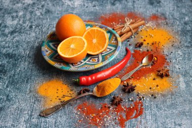 Portakallar, kırmızı biber, kırmızı biber tozu, zerdeçal ve üst görüntü fotoğrafı. Baharatlar masada. Baharatlı yemek hazırlığı yapılıyor. Meyveli renkli natürmort. 