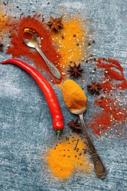 Kırmızı biber, kırmızı biber, zerdeçal, tarçın, anason yıldızı ve masada iki kaşık şarap. Aroma baharatlarının yakın plan fotoğrafını çek. Kopyalama alanı olan gri desenli arkaplan. 