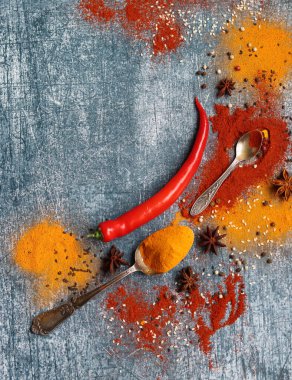 Kırmızı biber, kırmızı biber, zerdeçal, tarçın, anason yıldızı ve masada iki kaşık şarap. Aroma baharatlarının yakın plan fotoğrafını çek. Kopyalama alanı olan gri desenli arkaplan. 