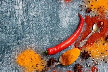 Kırmızı biber, kırmızı biber, zerdeçal, tarçın, anason yıldızı ve masada iki kaşık şarap. Aroma baharatlarının yakın plan fotoğrafını çek. Kopyalama alanı olan gri desenli arkaplan. 