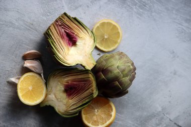 Masadaki taze sebzeler. Gri desenli masada pişmemiş enginarlar. Enginar çiçek dokusunun yakın fotoğrafını çek. Dengeli diyet kavramı.