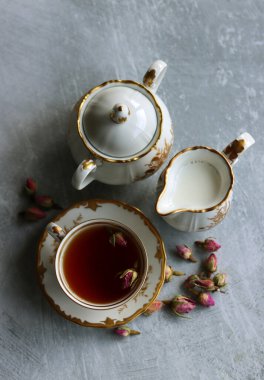 Güllü çay, yakın çekim fotoğrafı. Masadaki küçük beyaz seramik bardakta bitki çayı. Kopyalama alanı olan açık gri arkaplan. 