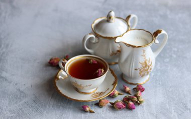 Güllü çay, yakın çekim fotoğrafı. Masadaki küçük beyaz seramik bardakta bitki çayı. Kopyalama alanı olan açık gri arkaplan. 